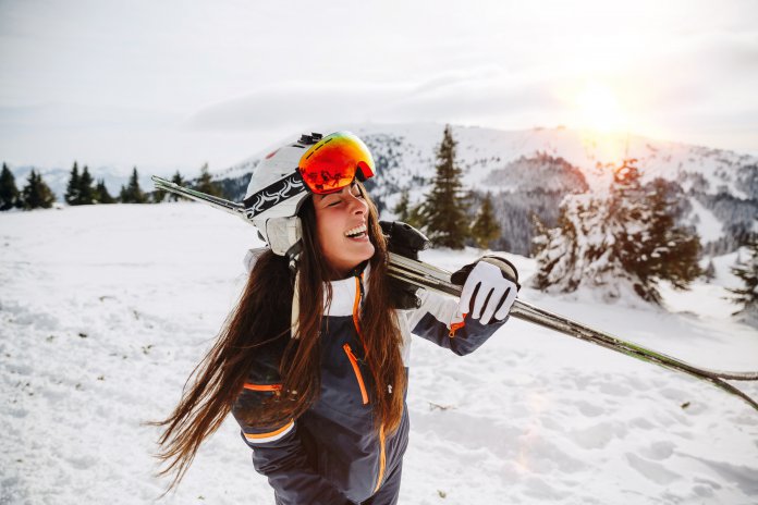 Portrait of beautiful woman with ski and ski suit in winter mountain